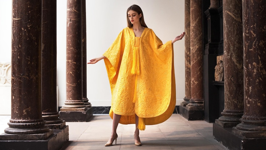 A model wears a hand-embroidered cape made from the naturally golden silk of the Orb spider.