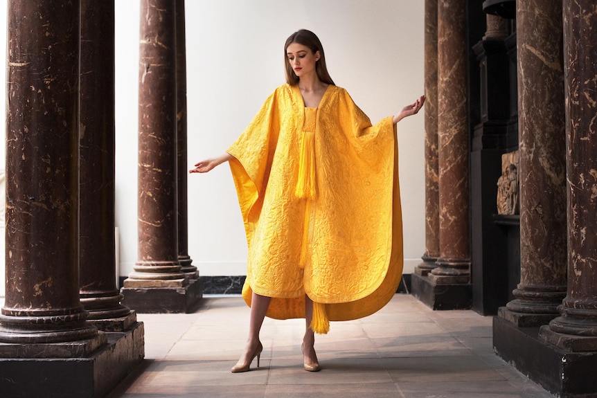 A model wears a hand-embroidered cape made from the naturally golden silk of the Orb spider.