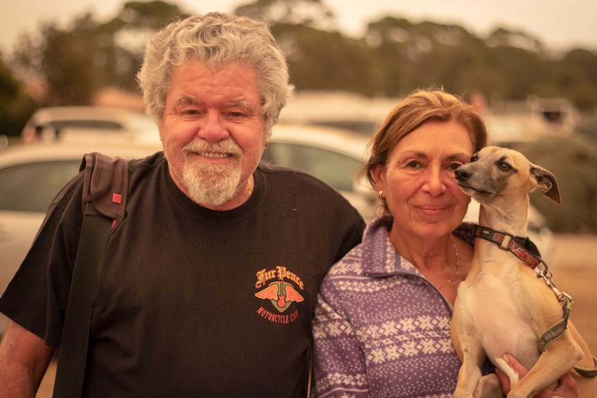 Michael and Nora look at the camera, Nora is holding a dog.