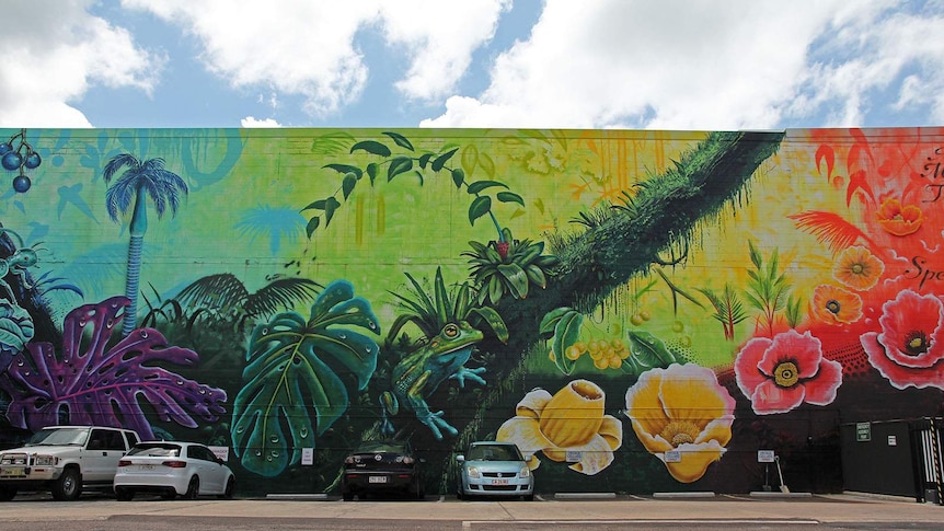 A photo of a brightly coloured tropical mural adjacent to a car park.