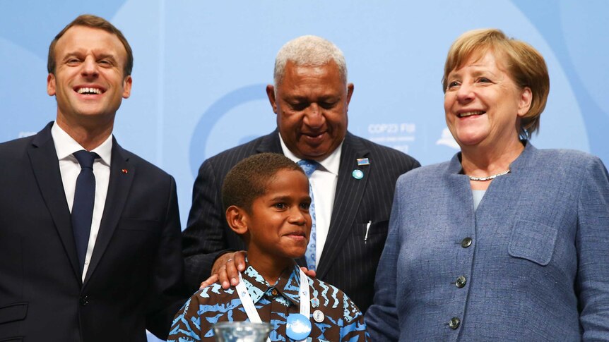 Emmanuel Macron,  Frank Bainimarama and Angela Merkel pose for a photo with a Fijian child at COP23 in Bonn.