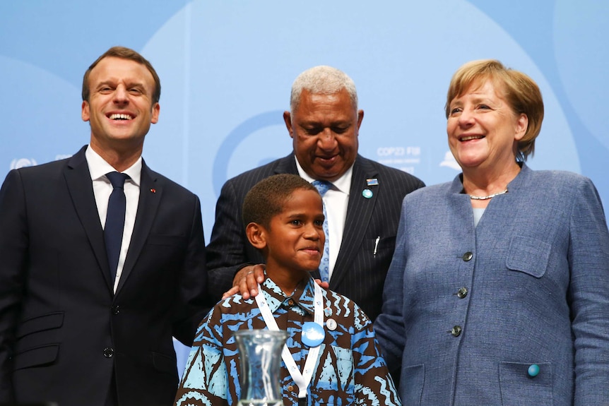 Emmanuel Macron,  Frank Bainimarama and Angela Merkel pose for a photo with a Fijian child at COP23 in Bonn.