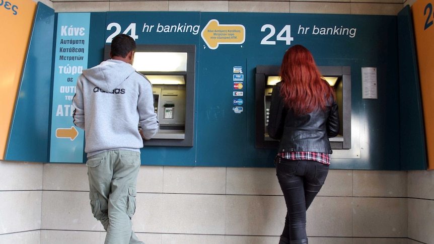 A man and a woman withdraw money from Cyprus ATMs