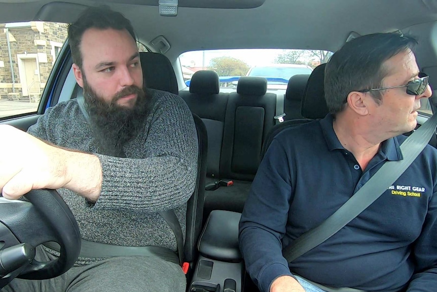 Two men in the front seats of a car.