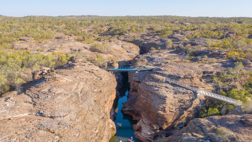 A drone image of a glass bridge in the middle of the outback, which is suspended above a gorge.