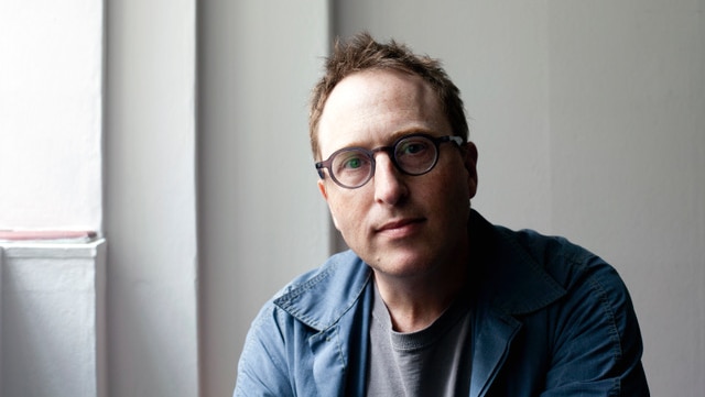 A man with glasses in a shirt looks at the camera