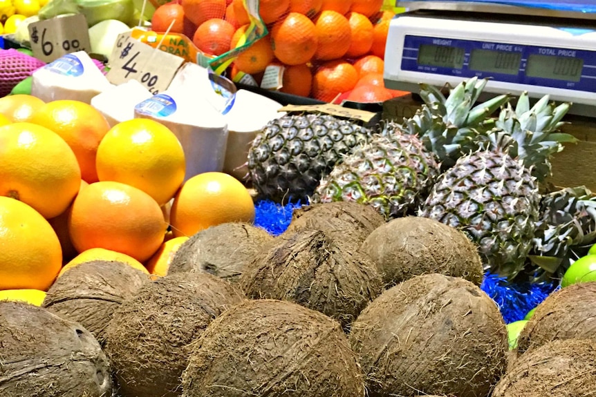 Tray of coconuts on a fruit and vegetable stall at a local market.