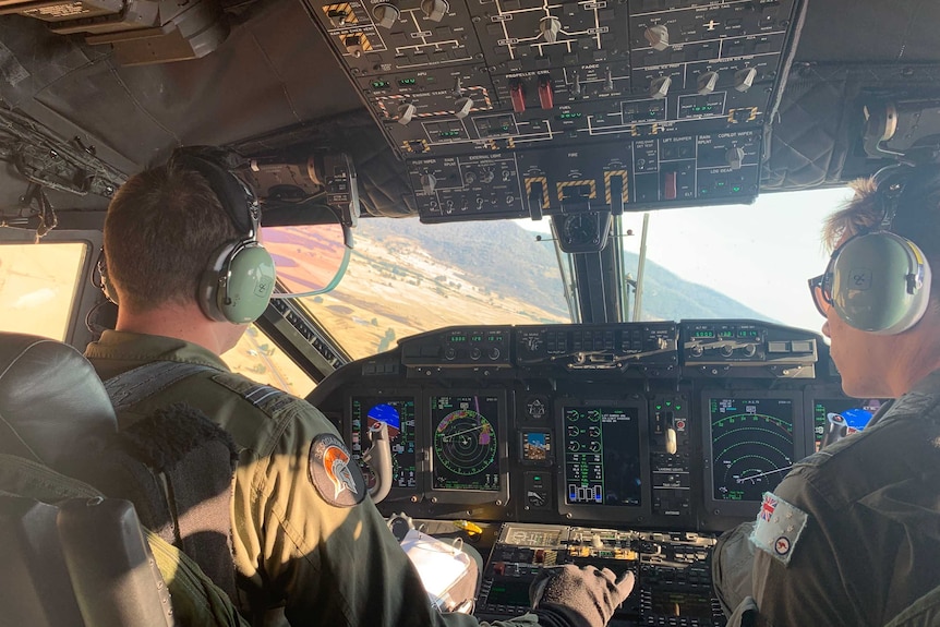 The view from the cockpit of a plane flying over dry, brown land.