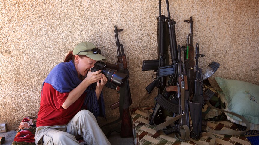 ABC journalist Tracey Shelton taking a photo of weapons.