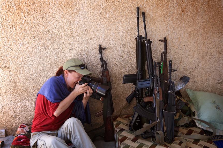 ABC journalist Tracey Shelton taking a photo of weapons.