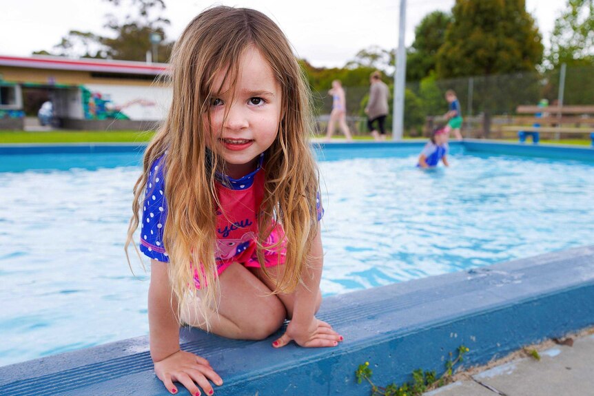 a young girl in front of a public swimming pool