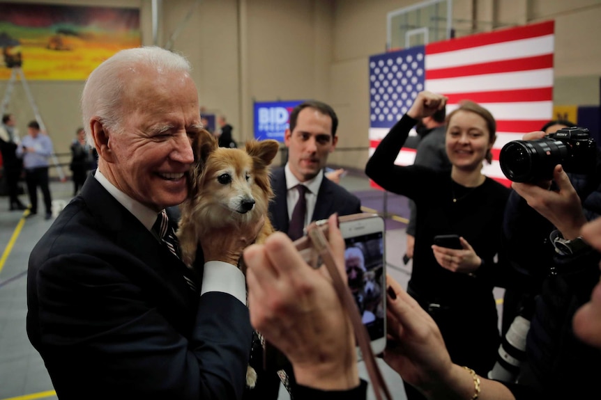 Joe Biden cuddles a dog while surrounded by supporters