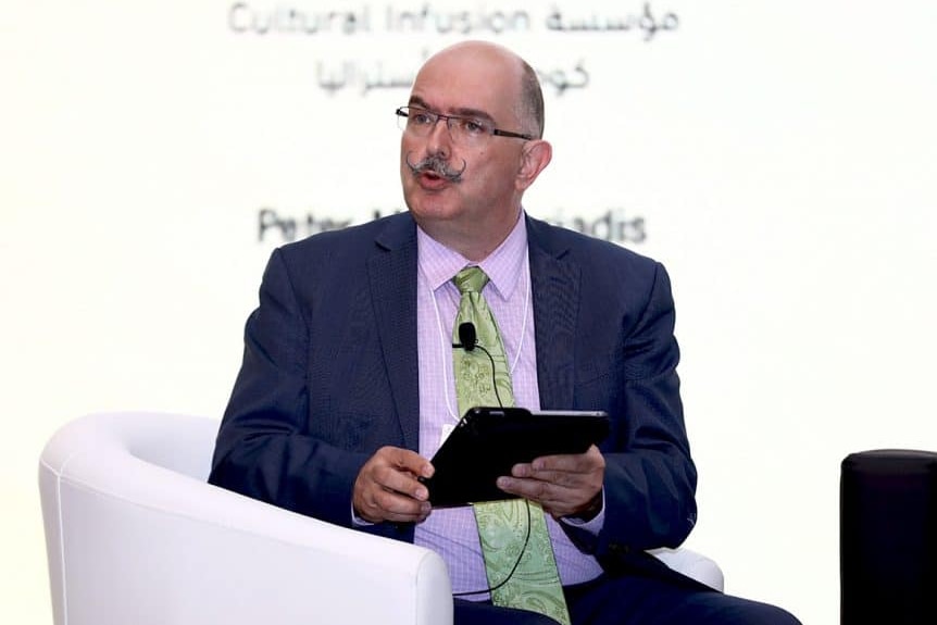 A man sitting on chair with an electronic device on his both hands.