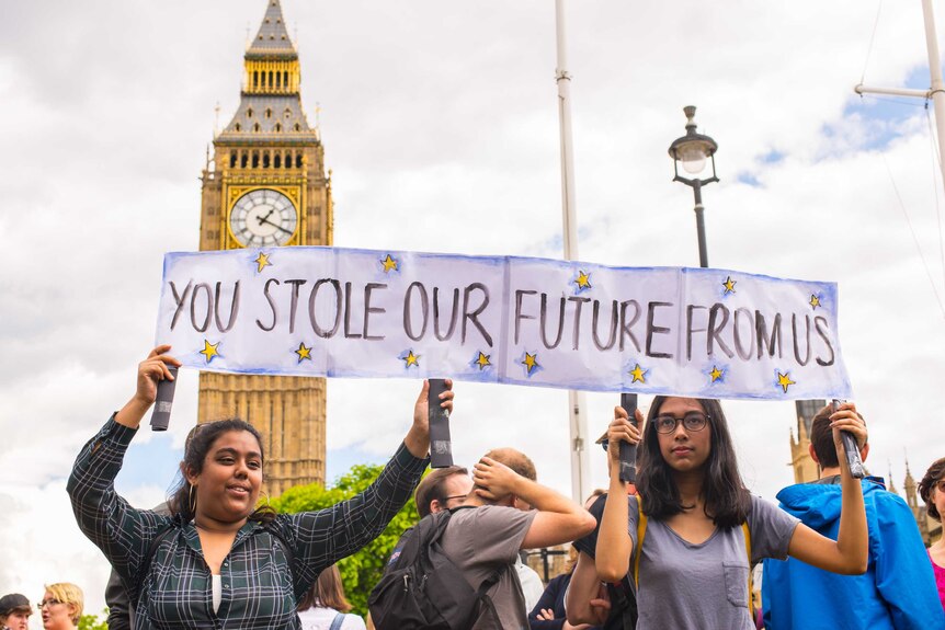 Two students hold protest sign with Big Ben in background