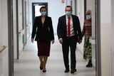 WA Health Minister Amber-Jade Sanderson and Premier Mark McGowan walk through a hospital corridor as a woman watches on