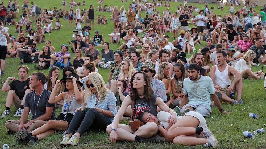 A crowd of young people sitting on a hill at Byron Falls Festival.