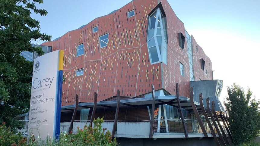 A modern-appearing orange building featuring unusual angles and geometric markings with a sign outside saying 'Carey'.