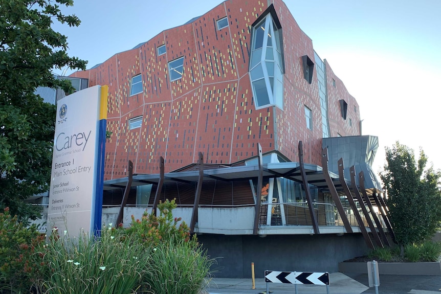 A modern-appearing orange building featuring unusual angles and geometric markings with a sign outside saying 'Carey'.