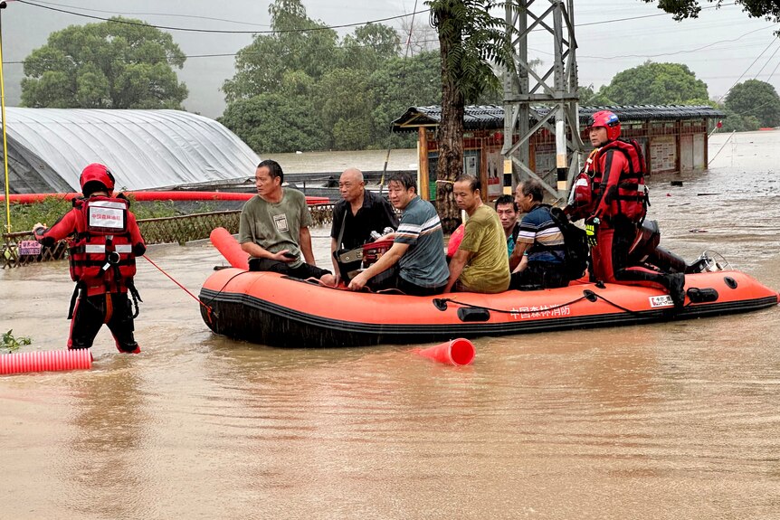 People sit in a rubber boat floating on floodwaters.