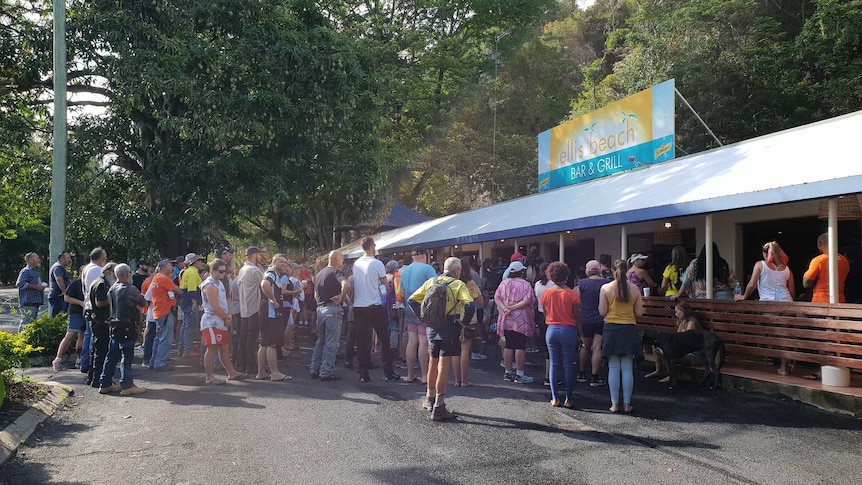 Hundreds of people gather at the Ellis Beach Bar and Grill in far north Queensland to hold a minute's silence