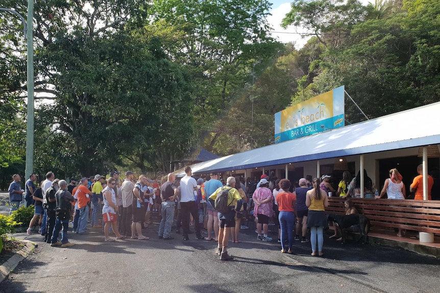 Hundreds of people gather at the Ellis Beach Bar and Grill in far north Queensland to hold a minute's silence