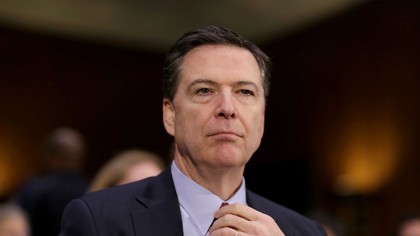 FBI Director James Comey adjusts his tie before testifying to the Senate Select Committee regarding
