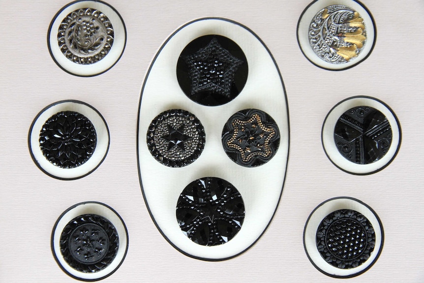 A collection of black glass buttons sitting on a cream background.