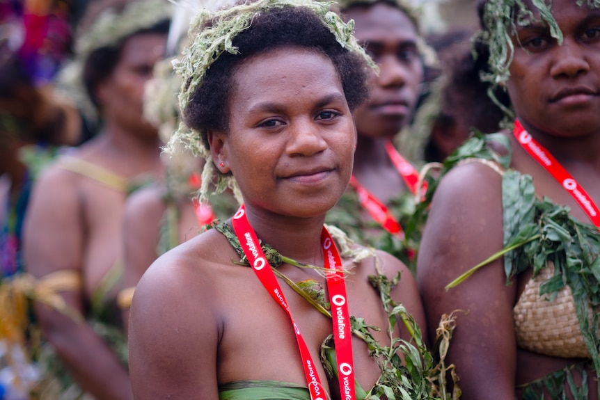 A Melanesian woman wearing a woven headpiece looks at the camera 