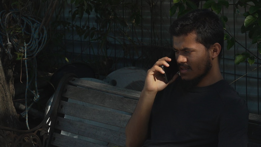 A man sitting outside talking on the phone.