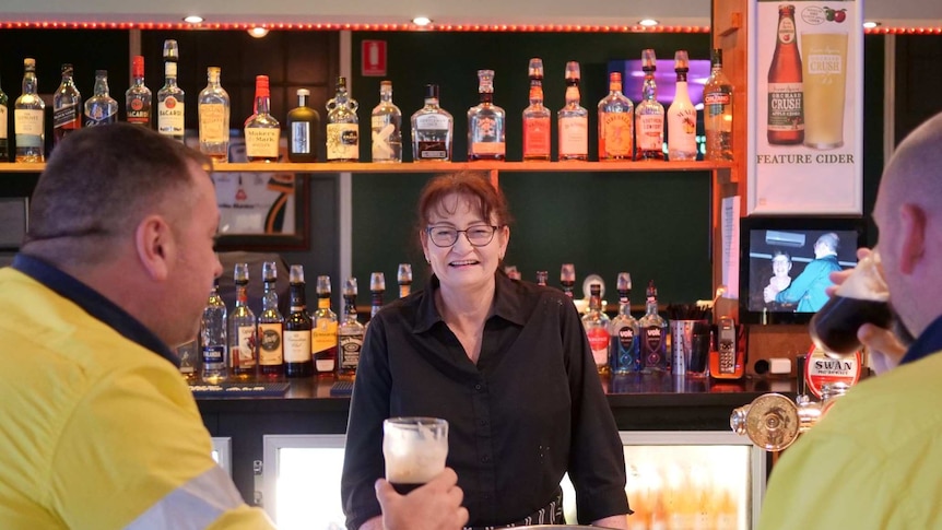 A bartender stands in front of customers