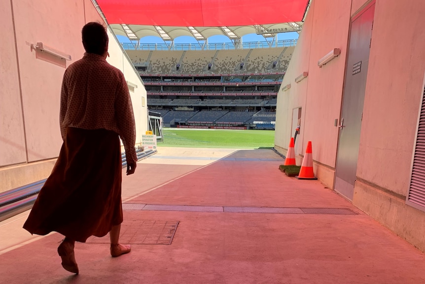 Photo taken from behind showing Jan Cooper walking towards the football field.