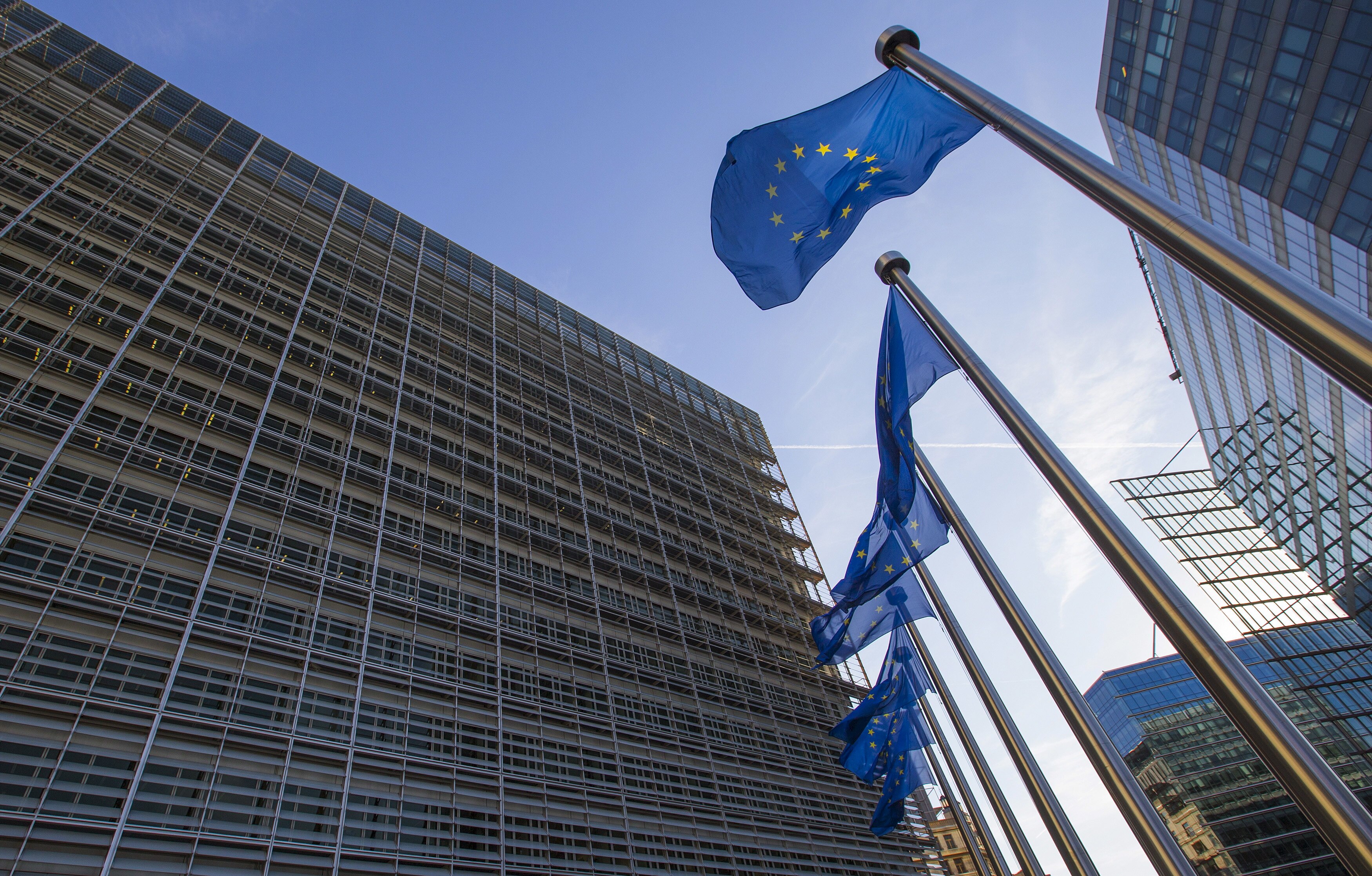 European Union flags fly on poles outside an office building 