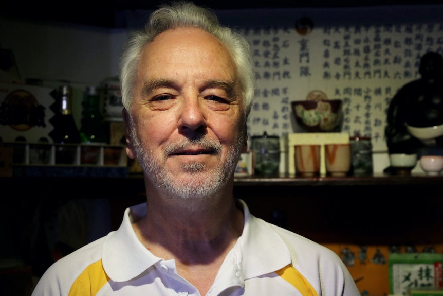 A japanese man wearing a polo shirt poses for a photo