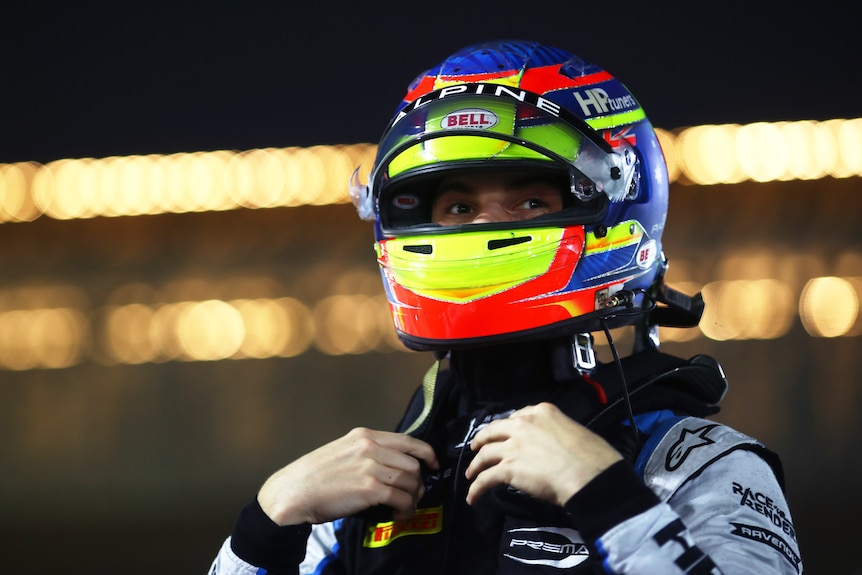 Racing driver with his helmet on looks forward.