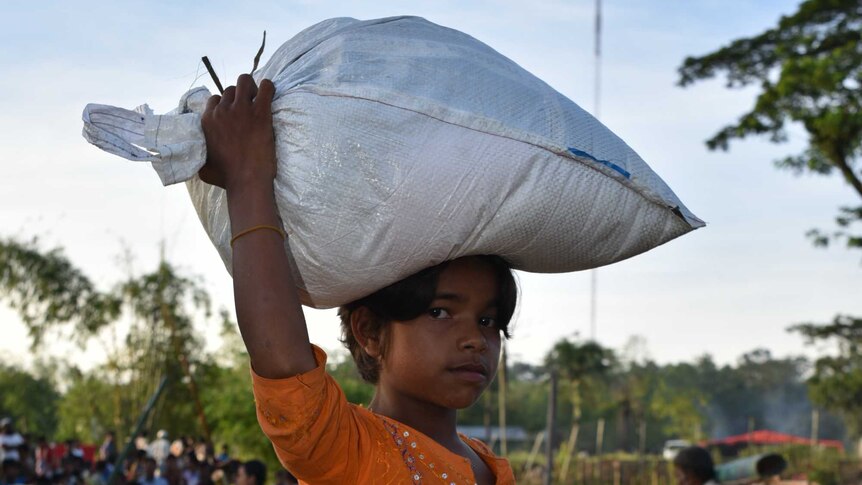 Shajeda carries a 20 kilogram bag of rice on her head.
