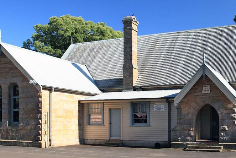 An exterior shot of a small old-fashioned stone school building.