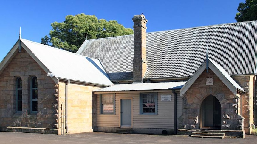 An exterior shot of a small old-fashioned stone school building.