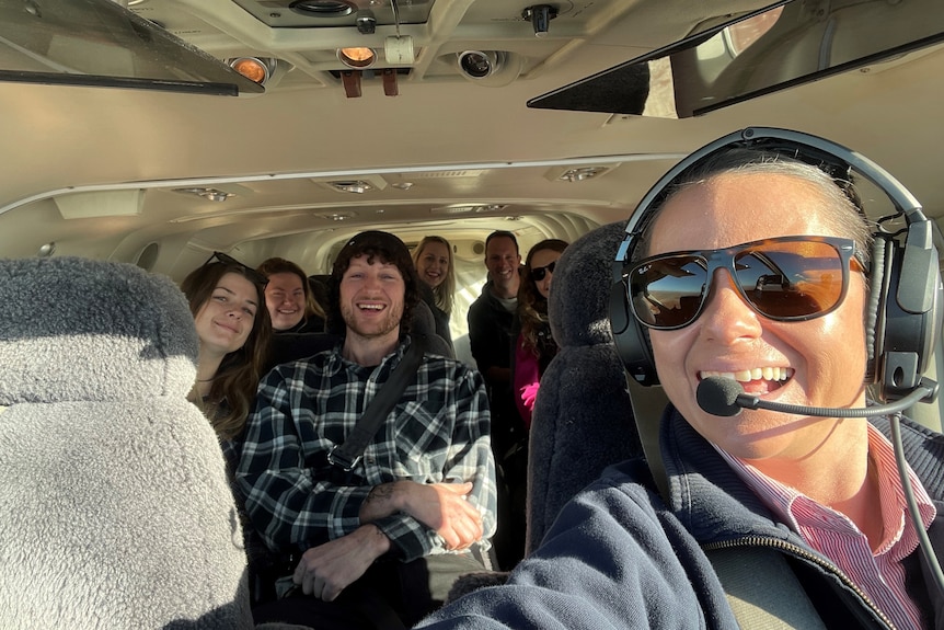 A young woman pilot taking a selfie in a plane with a group of people