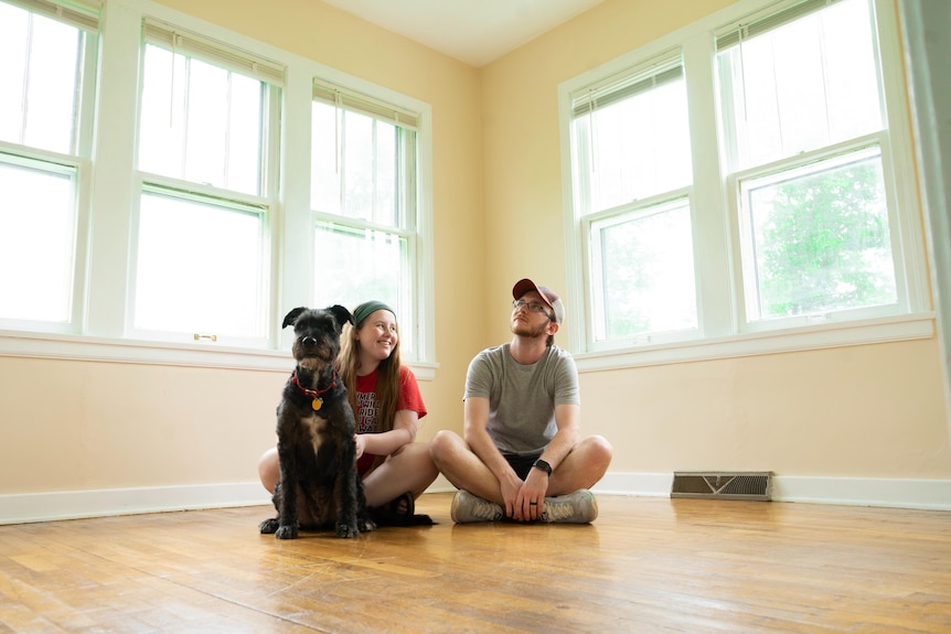 Young couple with dog sitting in empty new home