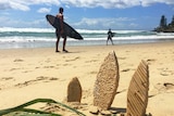 Small lemongrass surfboard prototypes sit in beach sand