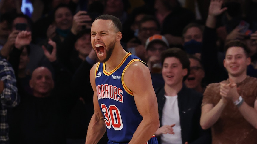 Steph Curry screams with his mouth wide open and his arms by his sides