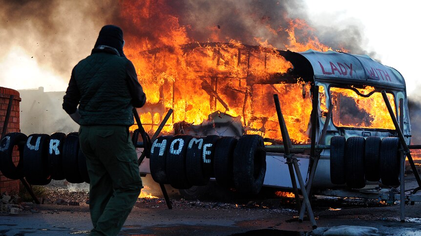 A caravan burns as riot police begin evicting travellers from Dale Farm