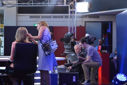 Camera crews and makeup artists prepare Antony green and a female presenter for an election night broadcast.