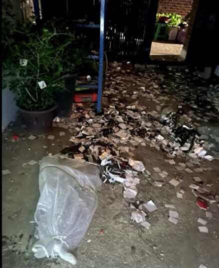 Trash spills out of a bag on a street at night