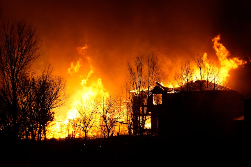 Homes burn as wildfires rip through a housing development.