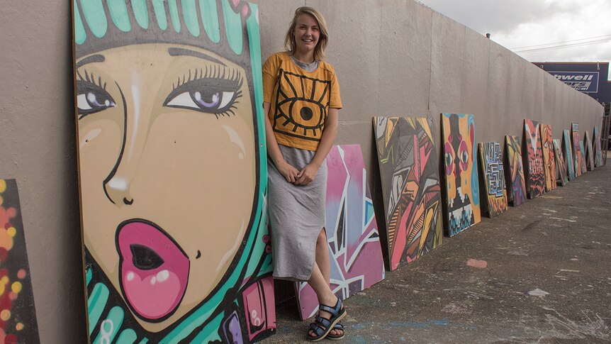 Grace Dewar from Toowoomba's First Coat festival stands with the reclaimed artworks