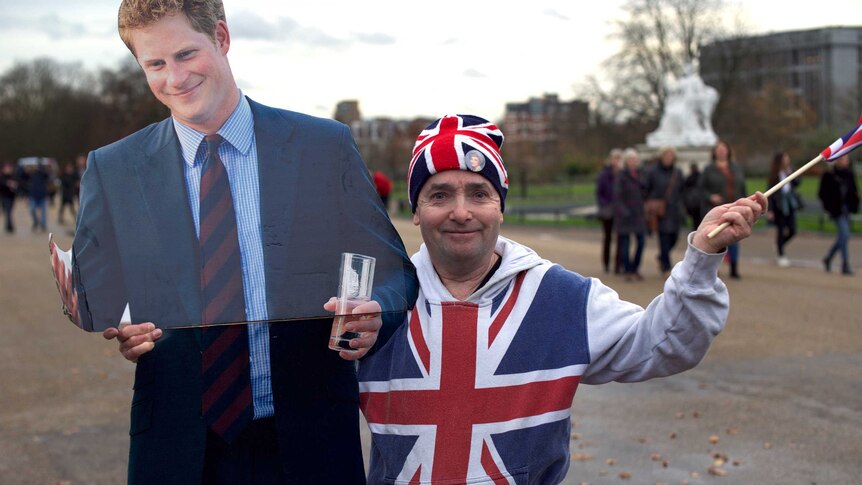 Royal watcher John Loughery dressed in clothes resembling the British flag poses with a cardboard cut out of Prince Harry