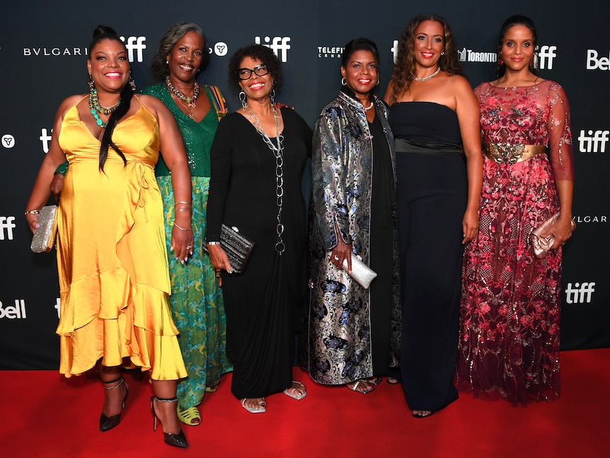 Six members of Sidney Poitier's family in dresses on a red carpet