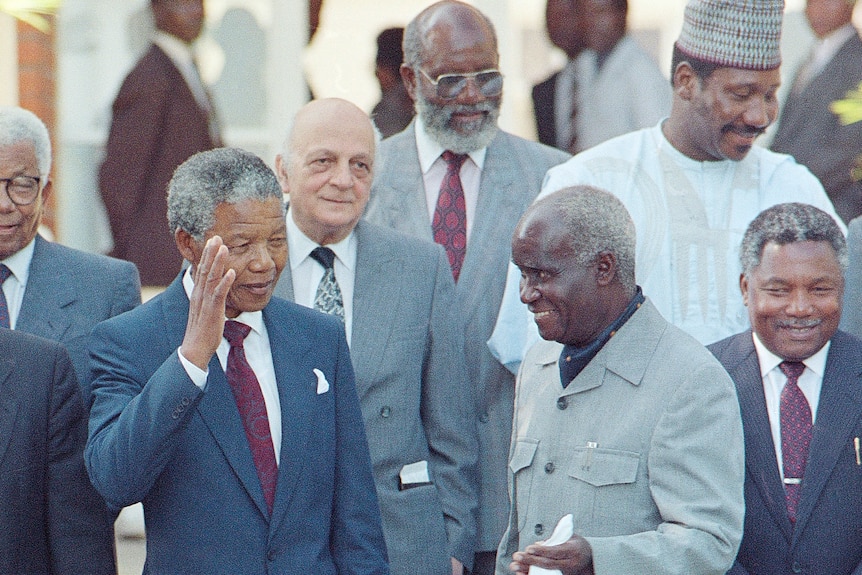 Nelson Mandela and Kenneth Kaunda stand together smiling. 
