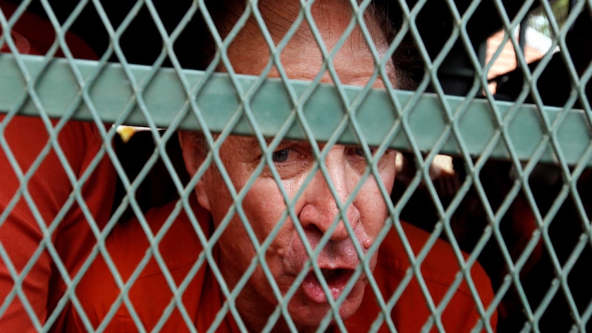 James Ricketson has his head up against caging as he speaks to journalists.